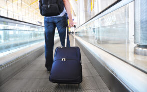 Traveler walking on a moving sidewalk pulling one of the best backpacks with wheels