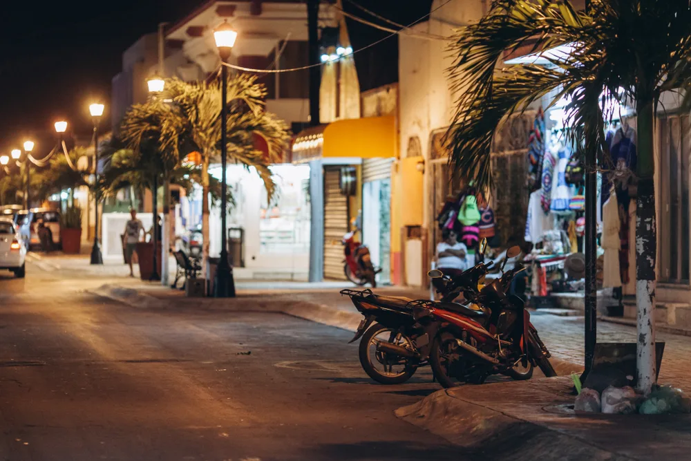 Dimly lit neighborhood on a street with little shops for a piece on Is Cozumel Safe to Visit