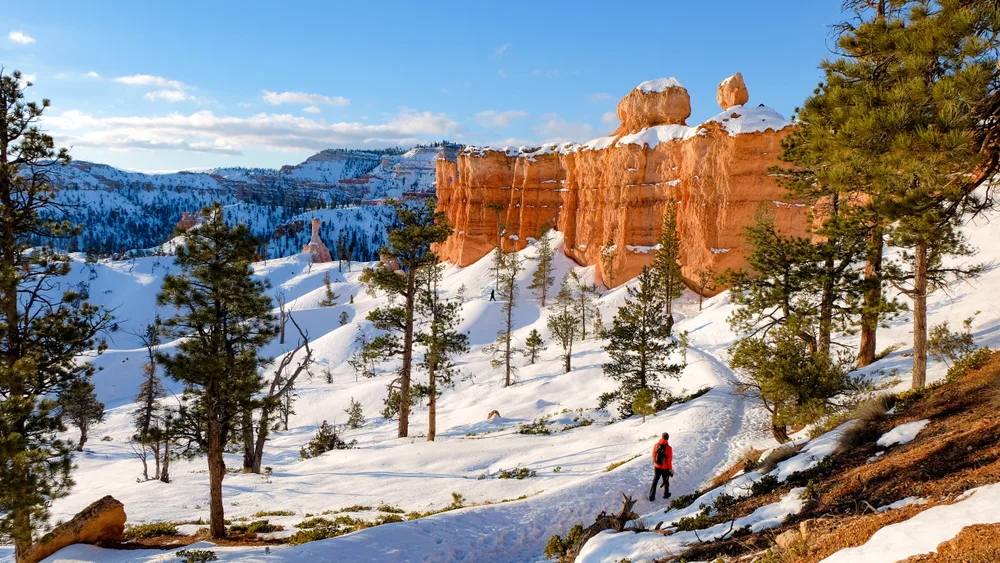 Guy walking along snowy trails in Least Busy Time to Visit Utah National Parks, one of the least busy times to visit Utah's national parks