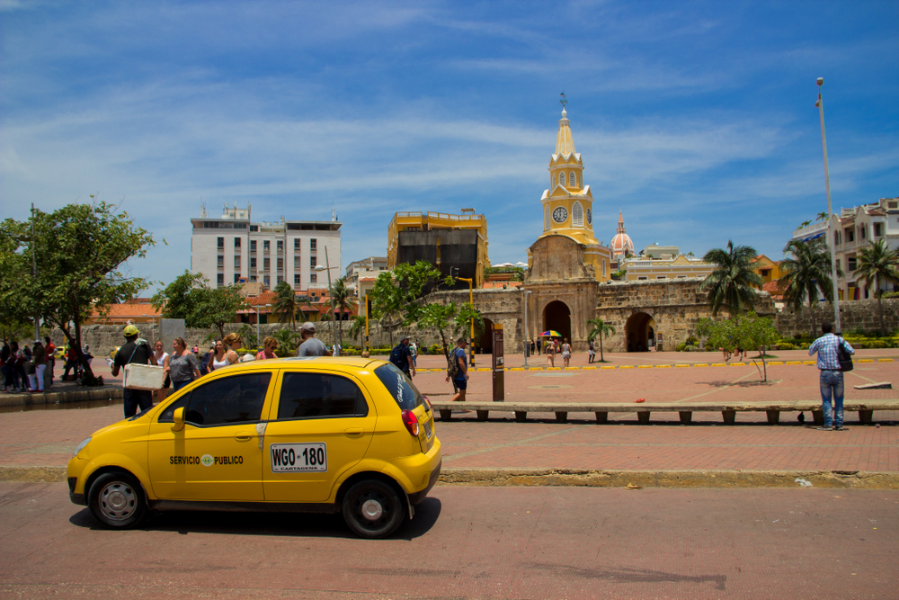 Clock tower over a monument with a taxi in Cartagena