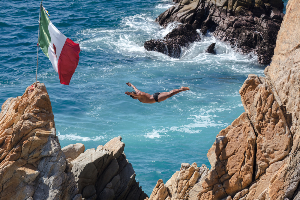 For a piece titled is Acapulco Safe to Visit, a Mexican cliff diver jumps off a rock