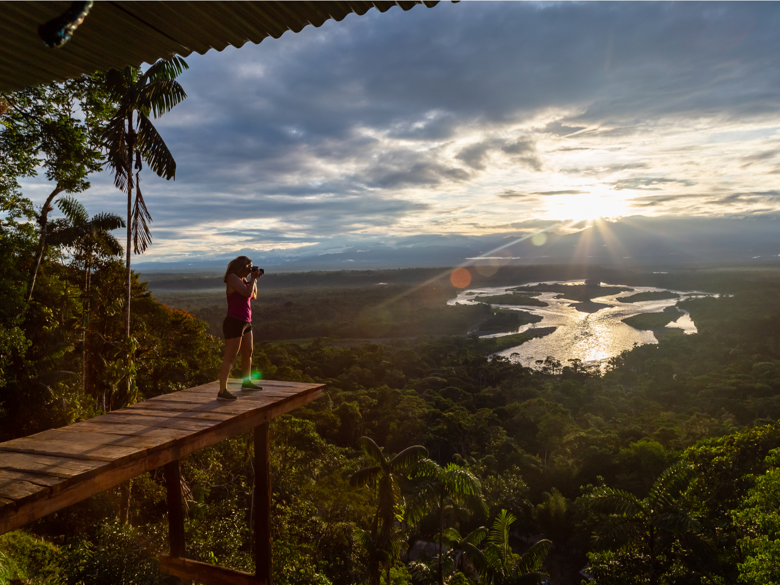 Woman in Puyo pictured taking a photo from a wooden platform for a piece titled Is Ecuador Safe to Visit