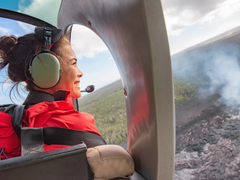 A woman smiling while looking at the natural view from a Helicopter, one of the best things to do in Oahu