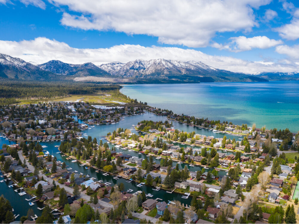 Aerial view of South Lake Tahoe with homes with docks in their backyard in the foreground and a giant mountain in the background