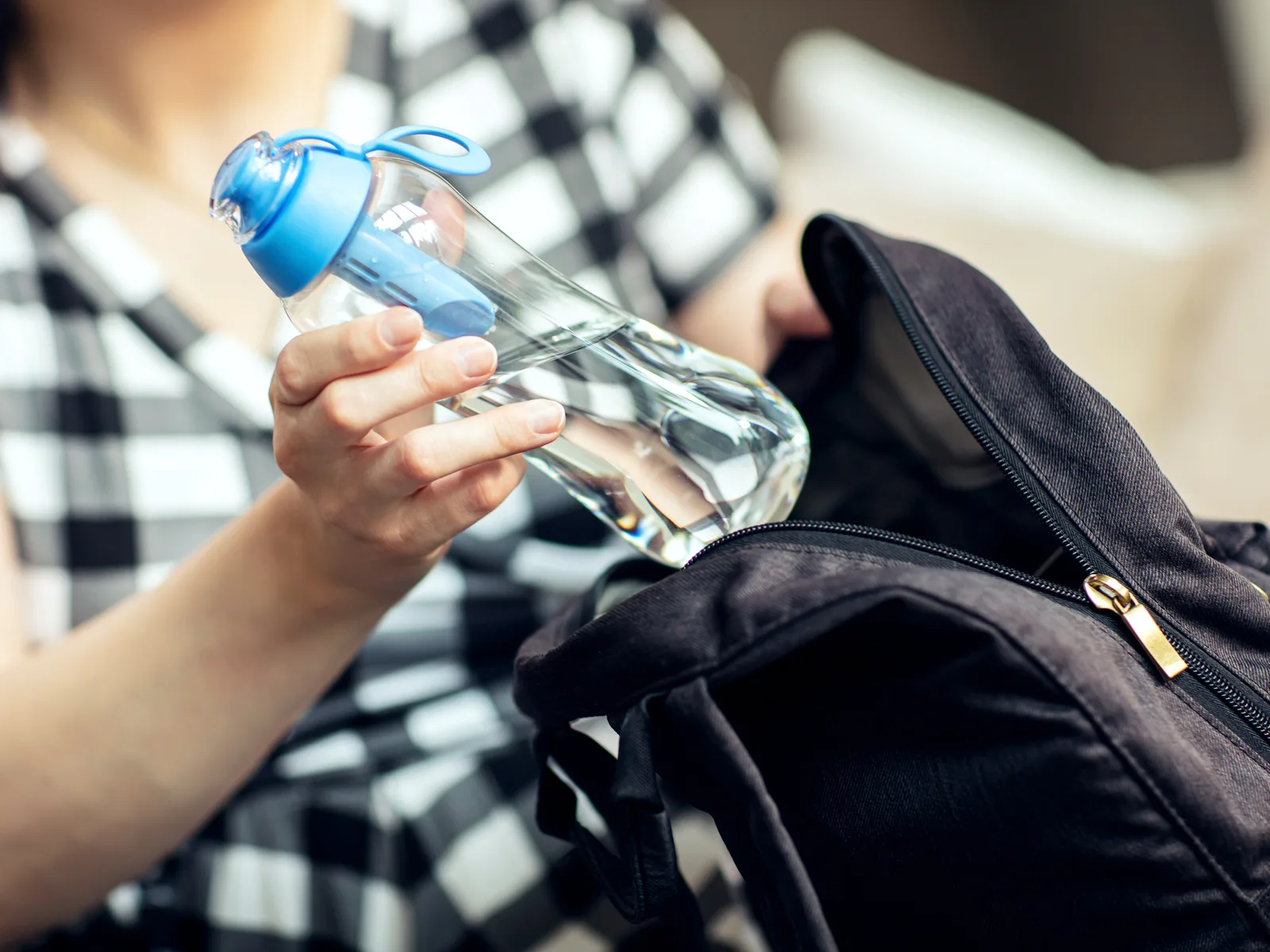 Woman takes a filtered water bottle out of her backpack