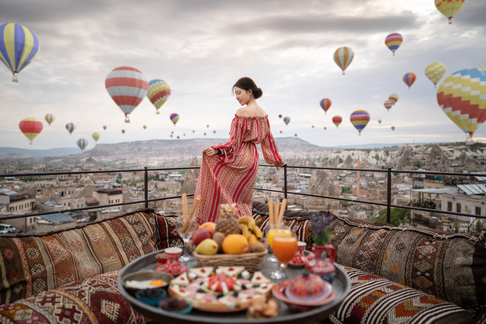 Woman on a roof of Cappadocian home overlooking the hot air balloons for a guide titled Is Turkey Safe to Visit