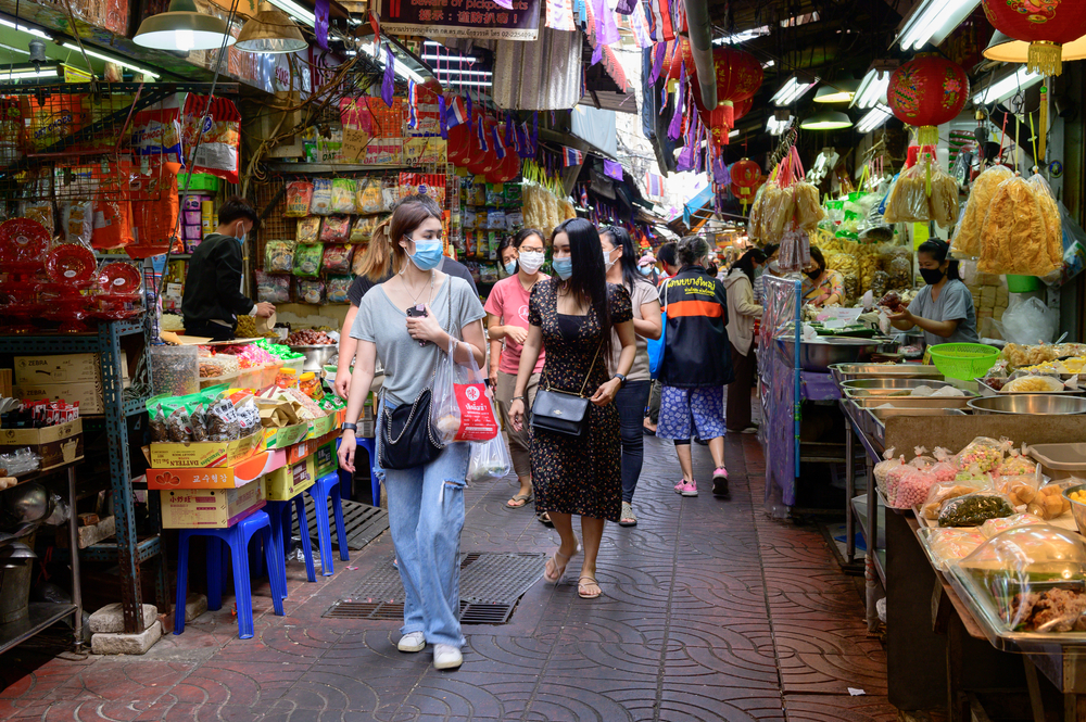 People in Bangkok pictured walking in a market for a guide to whether Thailand is Safe