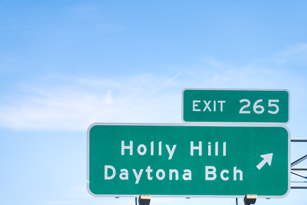 Holly Hills sign with an arrow above a highway for a piece titled Is Daytona Beach Safe