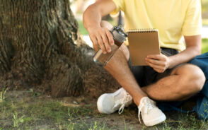 As the cover image for a piece on the best filtered water bottles, a young man holds such a product while studying by a tree