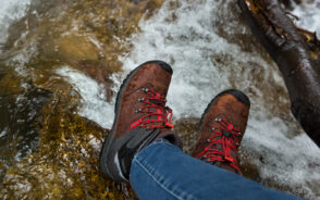 Guy putting his feet and the best waterproof hiking boots in the river