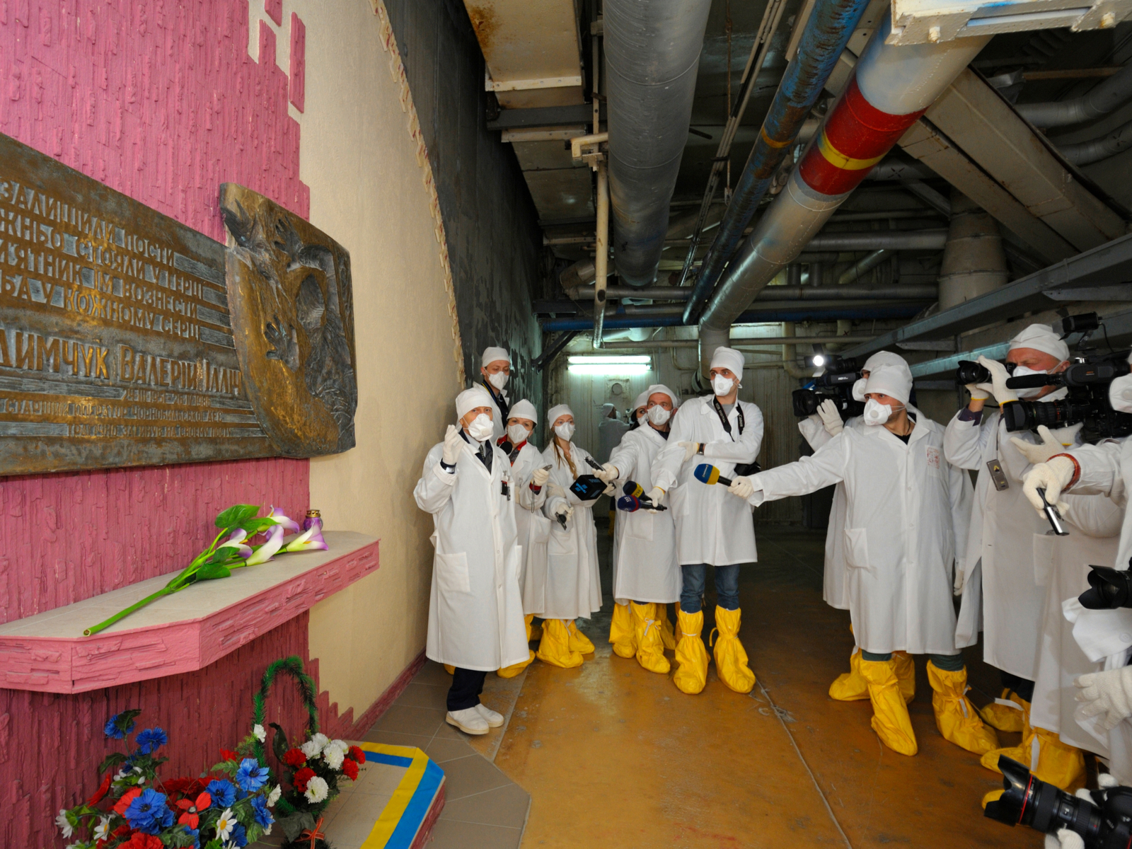Journalists standing near monument to Chernobyl Liquidators situated inside of building of Chernobyl Nuclear Power Plant. Press-tour to ChNPP for mass-media. April 20,2018. Chernobyl, Ukraine for a piece titled Is Chernobyl Safe