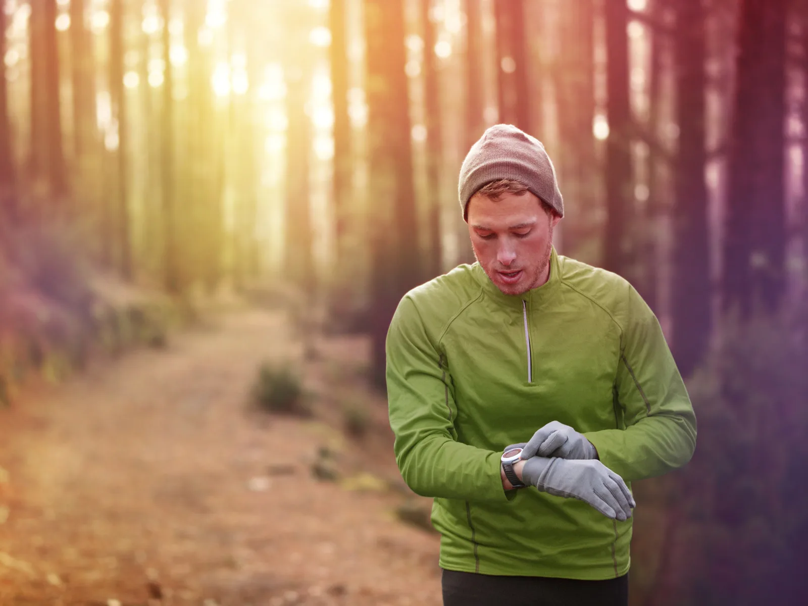 For a piece on the best outdoor watches, a guy looks at his wrist while wearing running gear in the forest