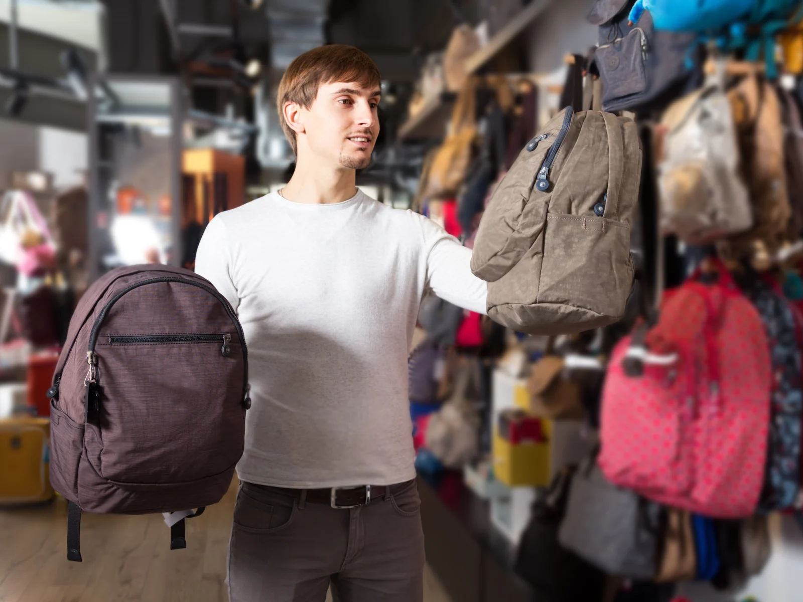 Man looking through the store trying to find the best backpack with wheels