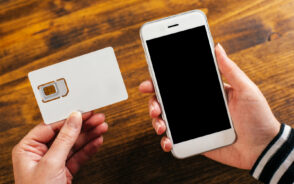 For a piece on the best international SIM cards, a person holding both a card and a mobile phone