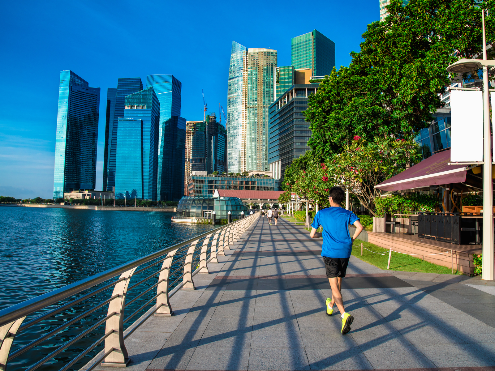 Guy running on the waterfront path during the best time to go to Singapore with clear sky and warm weather