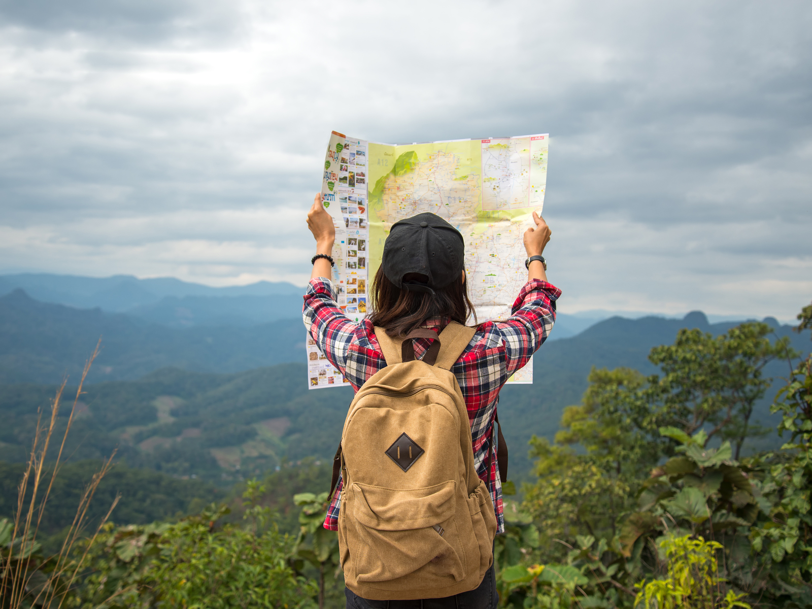 Woman holding a map up and wearing one of the best travel backpacks for women