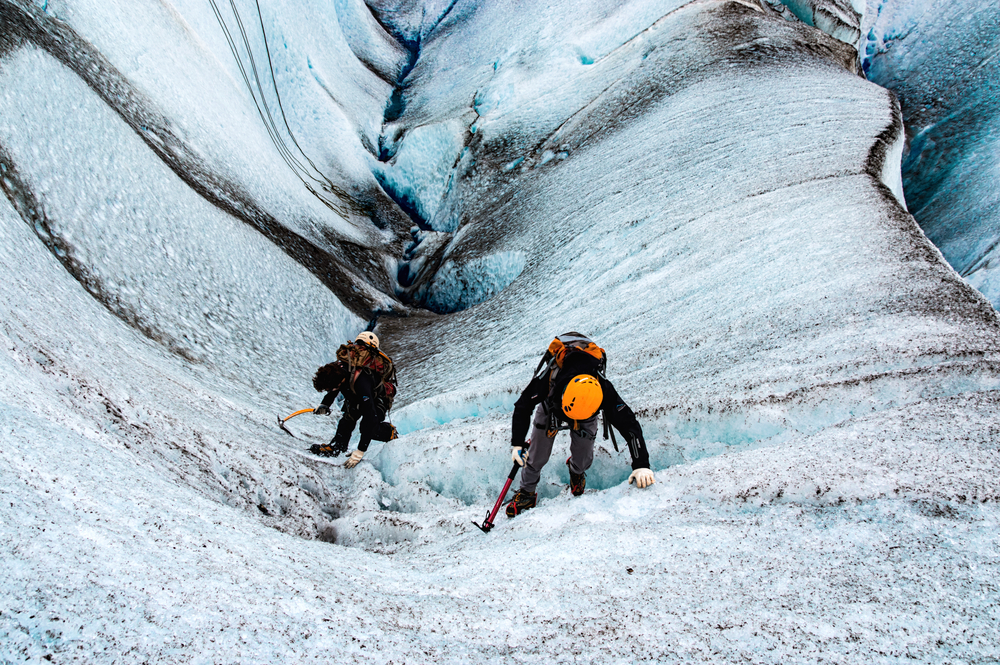 Two people climbing a frozen glacier in Patagonia during the cheapest time to visit