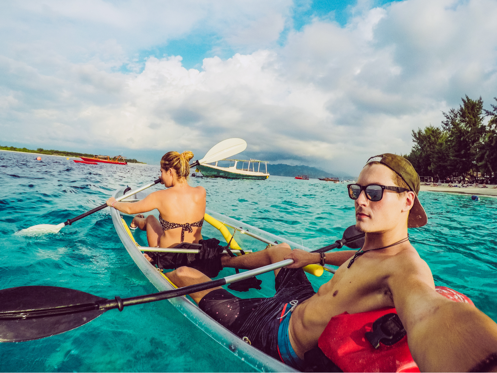 Couple in a kayak paddling on the ocean while the guy holds one of the best GoPro alternatives