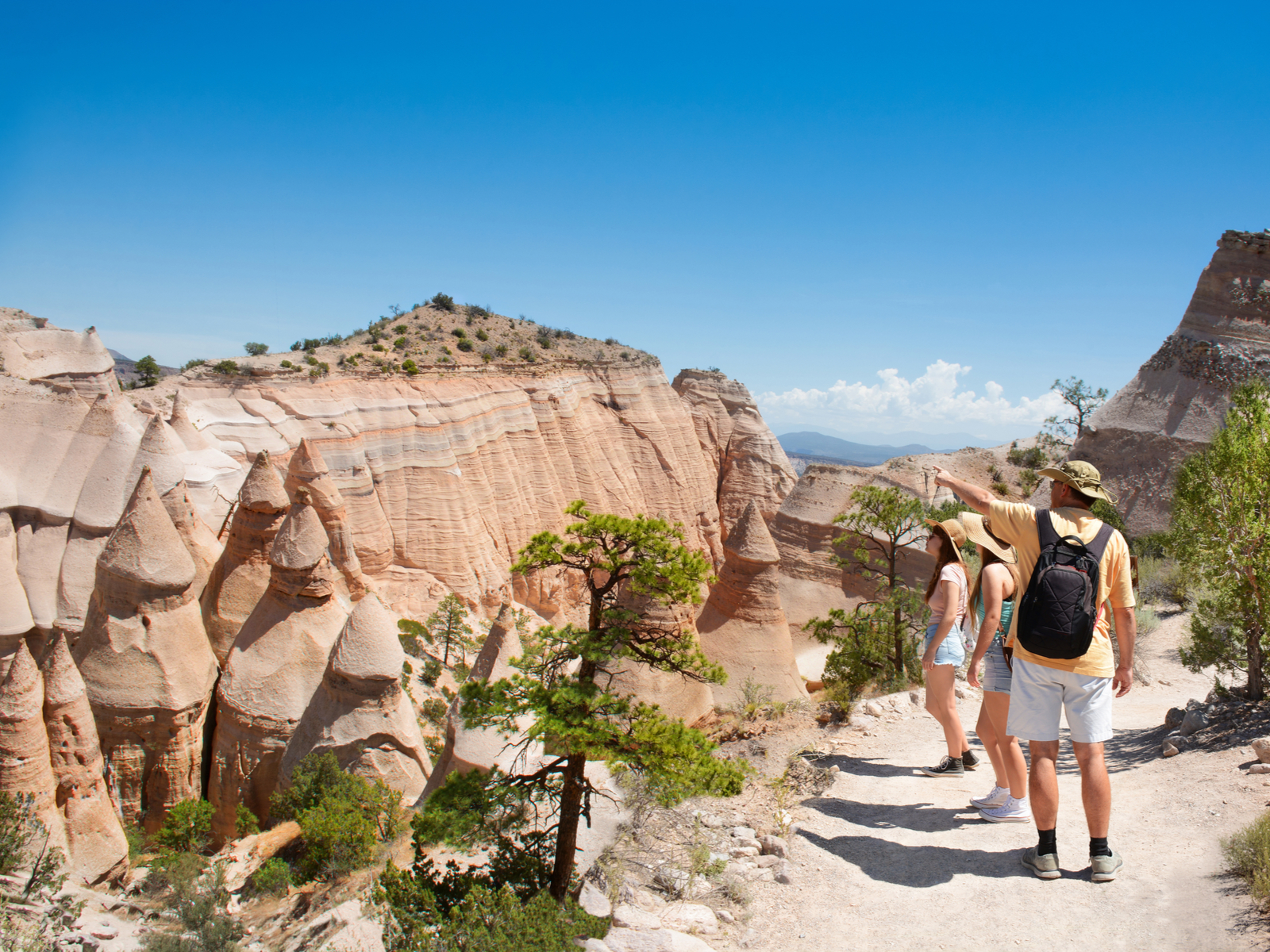 Guy walking through a hiking trail area with his family during the best time to visit New Mexico
