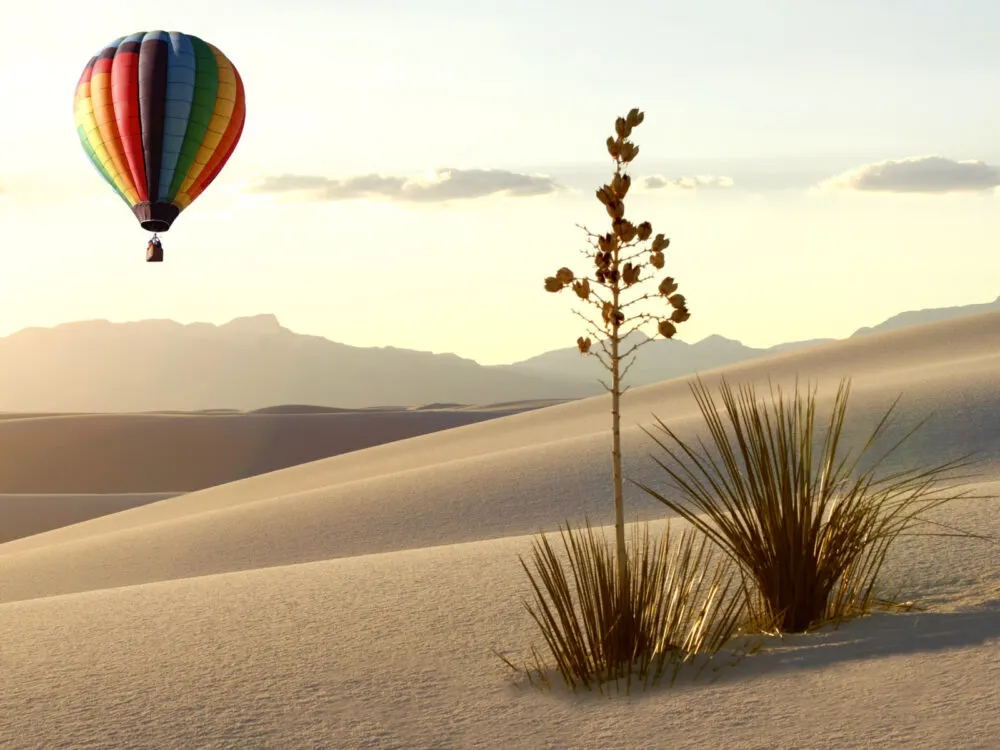Pictured during the worst time to visit New Mexico, the Summer, a hot air balloon is pictured over the white sands