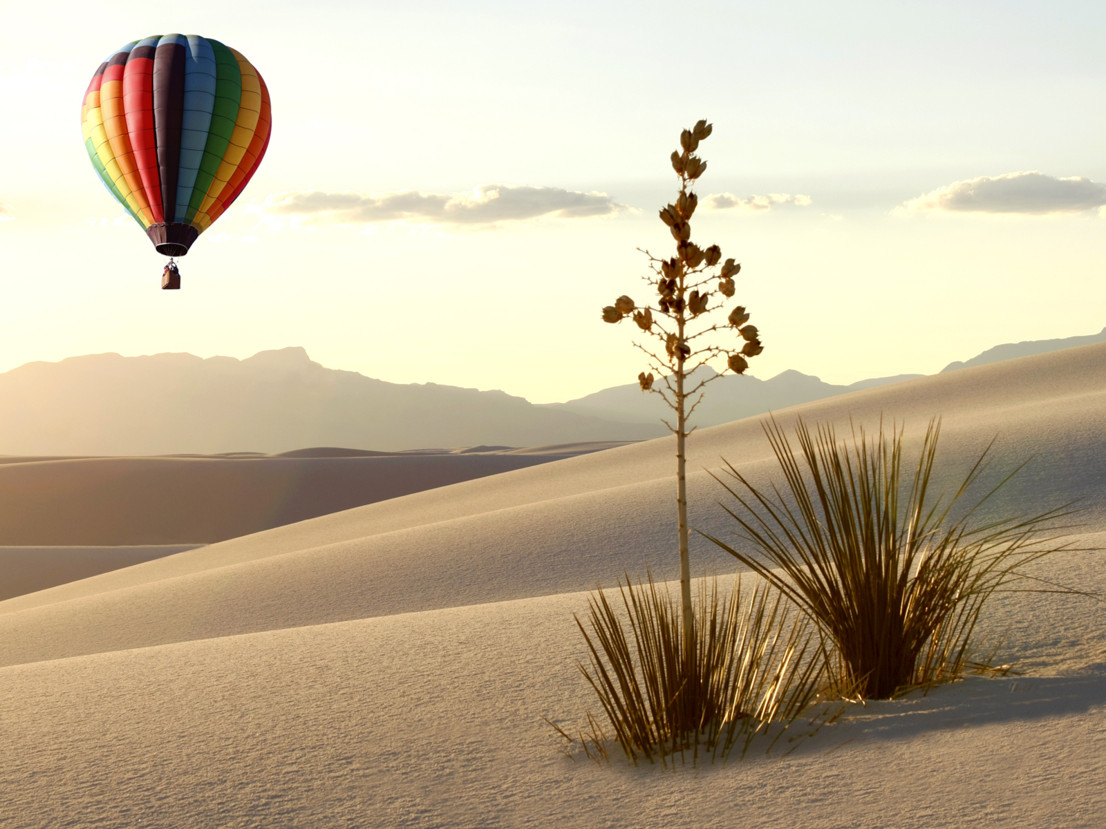 Pictured during the worst time to visit New Mexico, the Summer, a hot air balloon is pictured over the white sands
