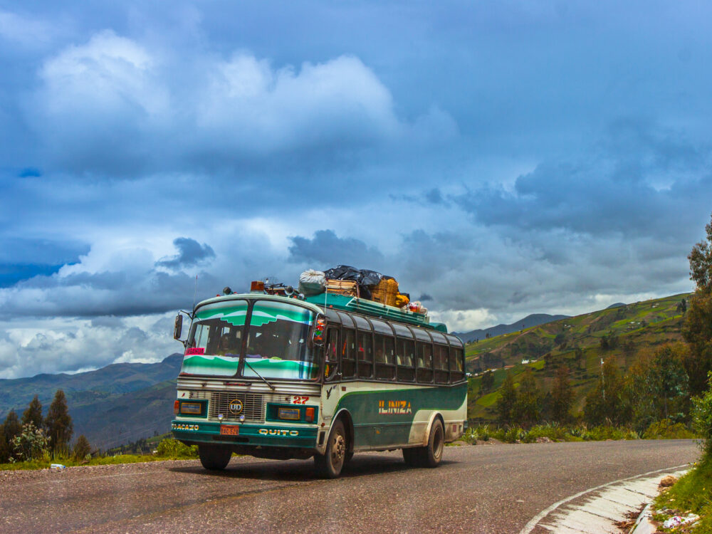 Green bus in the Andes pictured driving up a mountain for a piece titled Is Ecuador Safe to Visit