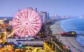 For a piece on where to stay in Myrtle Beach, a beach with a ferris wheel and boardwalk on a cloudy day in the evening