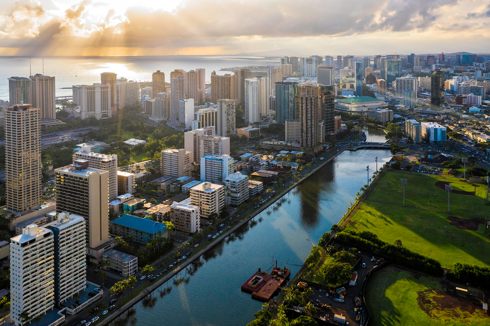 Downtown Honolulu pictured from the top of a building with the sun setting behind the clouds in the background