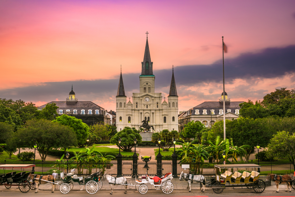 A sunset over the St. Louis Cathedral where horse taxis are on stand by while waiting for passengers outside its fence, one of the things to do in New Orleans.