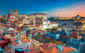 Featured image for a piece on where to stay in Porto, Portugal featuring the cityscape with the cathedral and old town pictured at sunset