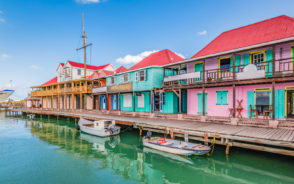 Colorful buildings along the boardwalk with small boats docked outside during the best time to visit Antigua