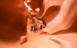 People walking through a gorgeous red-rocked canyon during the best time to visit Antelope Canyon
