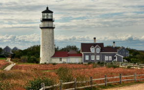 Gorgeous view of a lighthouse and home at dusk in the fall for a piece on where to stay in Cape Cod