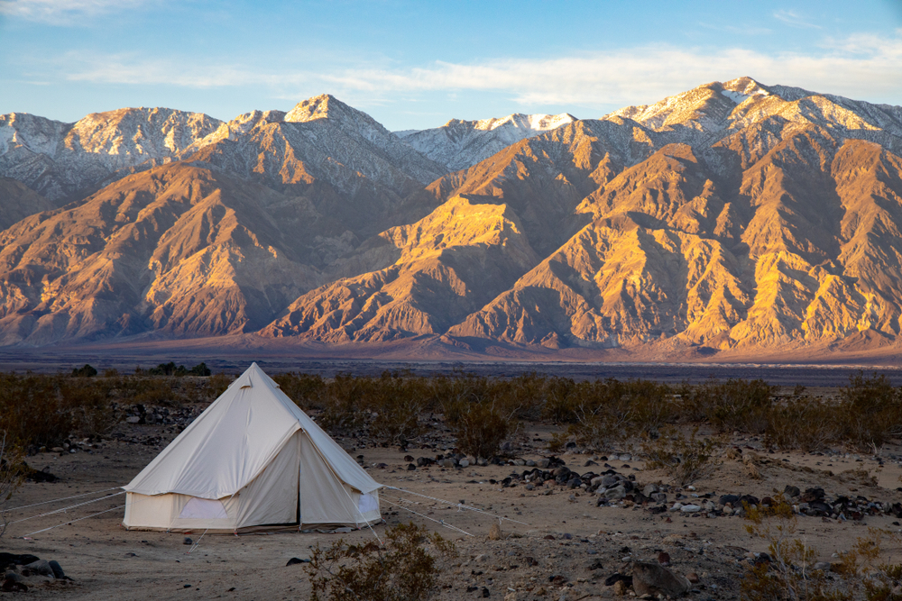 Person in a white tent camping outside the rock formations on a nice day for a piece on where to stay in Death Valley