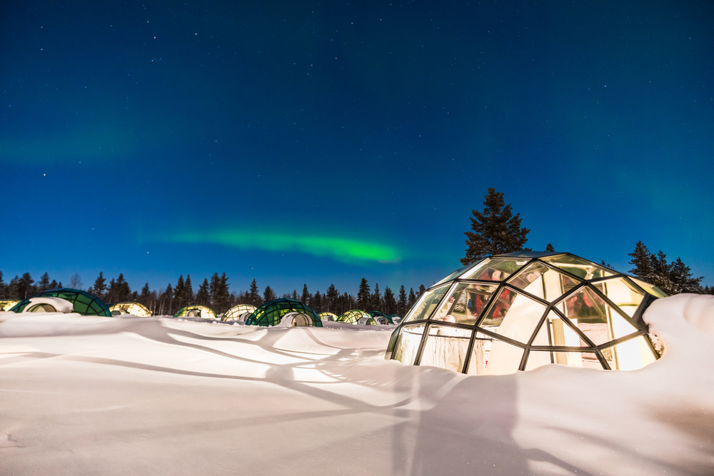 Northern lights as seen from the outside of a glass igloo home during the best time to visit Finland 