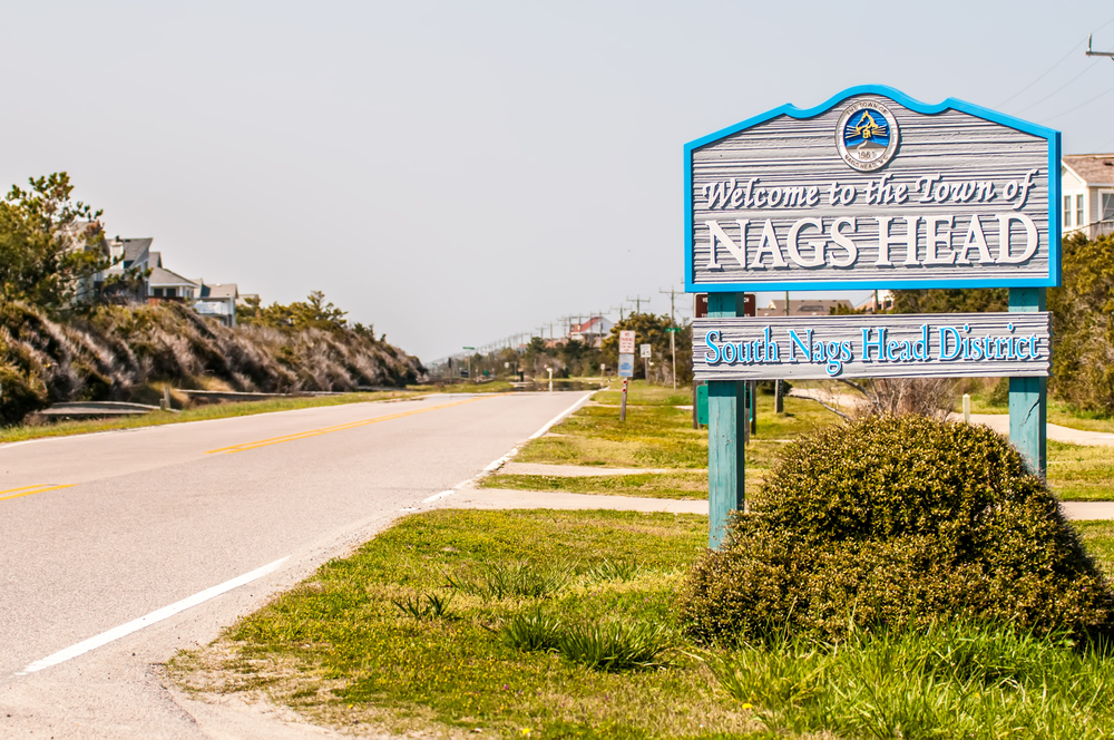Sign welcoming visitors to Nags Head next to a road on a semi-cloudy day for a piece on where to stay in the outer banks