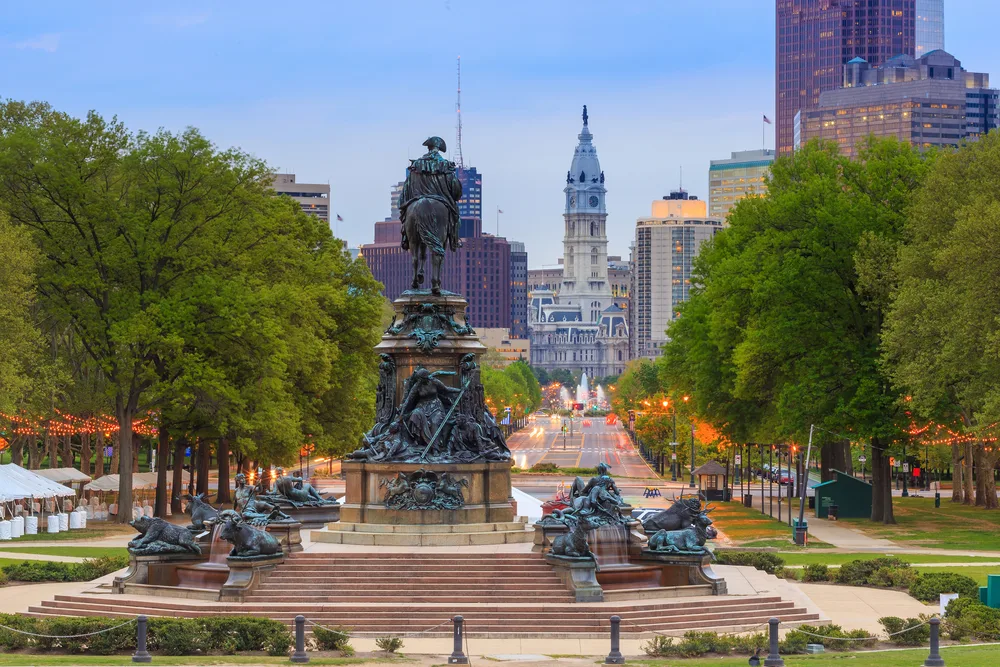 For a piece on where to stay in Philadelphia, a gorgeous view of city center pictured on a sunny day with a statue in the foreground and historical buildings in the background