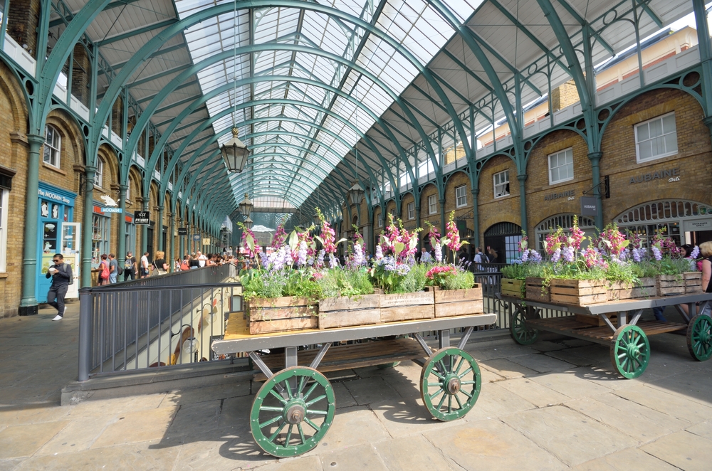 Photo of an indoor market in Convent Garden, one of the top picks when considering where to stay in London, with a wagon with planters on it