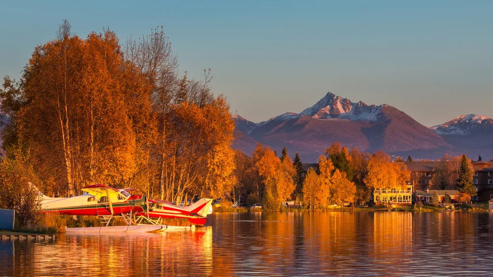 Anchorage Alaska in the middle of autumn with orange leaves over the lake with planes on it