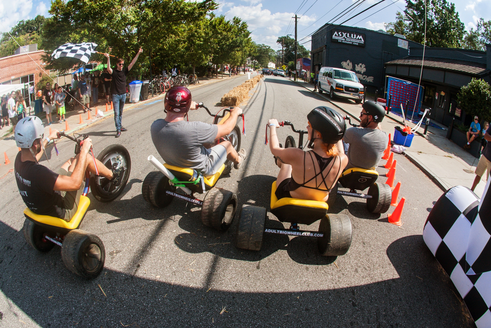 Photo of people riding trikes in the street in East Atlanta for a piece on where to stay when visiting Atlanta