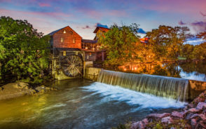 Gorgeous view of the mill and falls pictured lit up at dusk during the best time to visit Pigeon Forge, TN