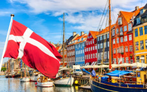 Famous Nyhavn port with Denmark flag waving showing the best time to visit Copenhagen