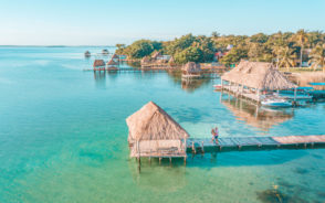 Aerial image of the Bacalar Pier, as seen from the air with teal blue water and a couple embracing on the dock during the best time to visit Riviera Maya