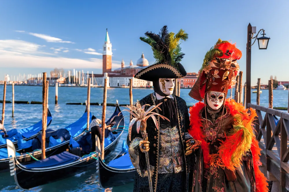 People wearing colorful Venetian carnival masks during the worst time to visit Venice