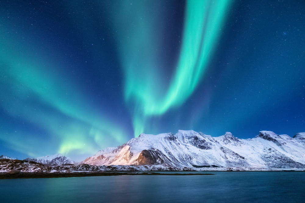  View of Alaska's Northern Lights view dancing across the sky over mountains with greenish blue color