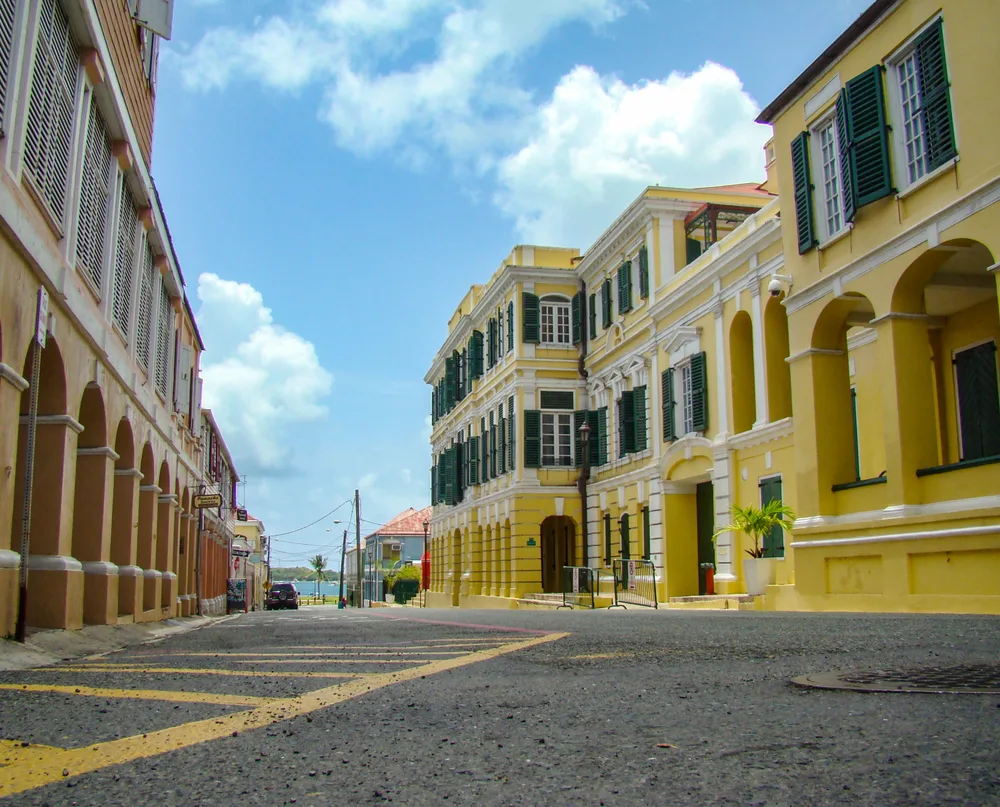 Yellow buildings pictured during the least busy time to visit the US Virgin Islands with nobody in the streets and a partial ocean view in the distance