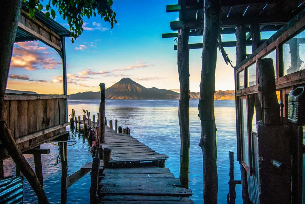 Sunrise as seen from a hut's walkway between support poles on Lake Atitlan during the best time to visit Guatemala