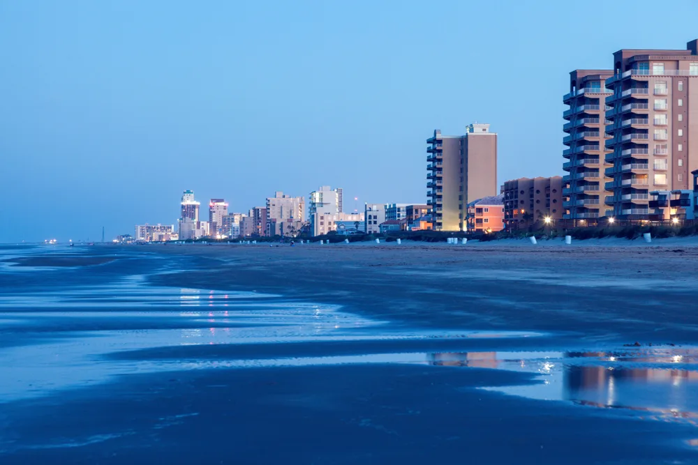 Beach view with buildings at dusk depicting why you should visit South Padre Island