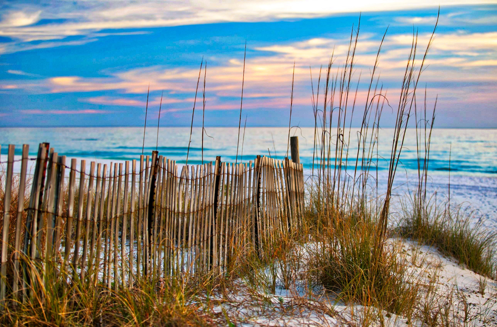Oceanfront fence on Long Beach with colorful sunset sky during the least busy time to visit Panama City Beach