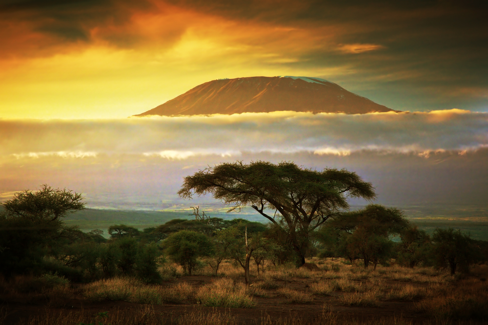 Mount Kilimanjaro in the distance with the sun rising over the mountain at dusk during the best time to visit Mount Kilimanjaro
